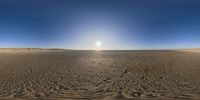 a camera pointed over a sandy beach with waves and sand on the shore and sunlight shining across the horizon