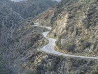 there is an aerial view of the scenic road going through the mountains and on the road are trees