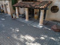 a brick street with a building and chairs at the entrance to a winery tasting area