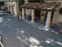 a brick street with a building and chairs at the entrance to a winery tasting area