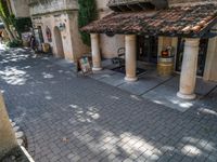 a brick street with a building and chairs at the entrance to a winery tasting area