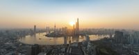 the sun shining over a city at sunset as seen from a tall building overlooking the river and water