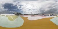 this skateboard park has skateboard ramps in it and a cloudy sky in the background