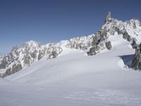 an aerial view of two skiers with mountain peaks in the background in wintertime