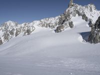 an aerial view of two skiers with mountain peaks in the background in wintertime