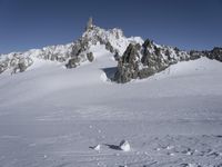 an aerial view of two skiers with mountain peaks in the background in wintertime