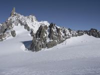 an aerial view of two skiers with mountain peaks in the background in wintertime