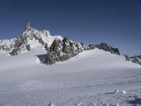 an aerial view of two skiers with mountain peaks in the background in wintertime