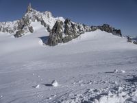 an aerial view of two skiers with mountain peaks in the background in wintertime