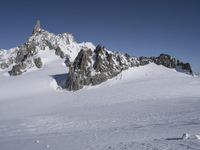 an aerial view of two skiers with mountain peaks in the background in wintertime