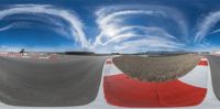 a fish eye lens photograph of a small track that is in the air with the red and white striped barrier