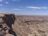 a very big canyon with a man sitting on it's edge looking over it