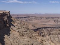 a very big canyon with a man sitting on it's edge looking over it