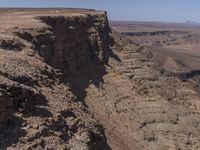 a very big canyon with a man sitting on it's edge looking over it