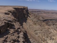 a very big canyon with a man sitting on it's edge looking over it