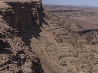 a very big canyon with a man sitting on it's edge looking over it