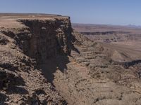 a very big canyon with a man sitting on it's edge looking over it