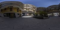 a fish eye view of some big buildings and plants in pots on the concrete floor