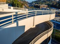 the top of a white overpass with traffic in the background is shown, and surrounded by trees