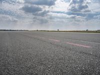 a large open air field under cloudy skies with a single plane on it's landing strip