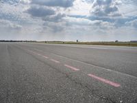 a large open air field under cloudy skies with a single plane on it's landing strip