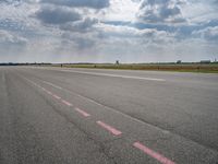 a large open air field under cloudy skies with a single plane on it's landing strip