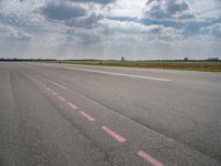 a large open air field under cloudy skies with a single plane on it's landing strip