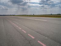 a large open air field under cloudy skies with a single plane on it's landing strip