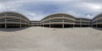 an oval picture of the sky behind a building and parking lot that contains multiple round - shaped buildings with multiple balconings