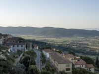 a long country road in front of a town with a view of a valley below