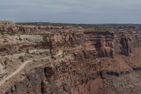 a canyon with rocks, shrubs and trees near by on a dirt road passing through them