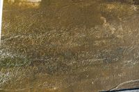 an image of the water flowing through the sand on a beach, with a person riding a surfboard