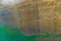 an aerial shot of a water surface with some sand on it and green grass surrounding