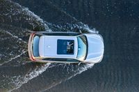 an aerial view of a white vehicle driving through water in the middle of a body of water