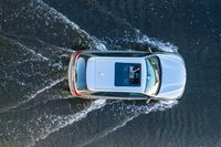 an aerial view of a white vehicle driving through water in the middle of a body of water