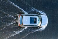 an aerial view of a white vehicle driving through water in the middle of a body of water