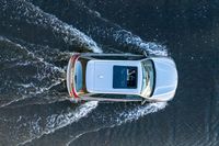 an aerial view of a white vehicle driving through water in the middle of a body of water