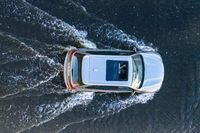 an aerial view of a white vehicle driving through water in the middle of a body of water