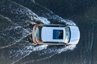 an aerial view of a white vehicle driving through water in the middle of a body of water