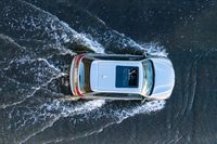 an aerial view of a white vehicle driving through water in the middle of a body of water