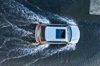 an aerial view of a white vehicle driving through water in the middle of a body of water