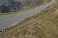 a motorcycle parked on a small mountain side road near mountains with no cars driving on it