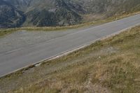 a motorcycle parked on a small mountain side road near mountains with no cars driving on it