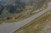 a motorcycle parked on a small mountain side road near mountains with no cars driving on it