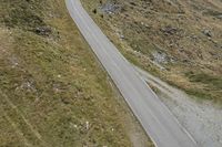 a motorcycle parked on a small mountain side road near mountains with no cars driving on it