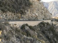 a road is winding away from the mountainside and steep slope of the valley, which runs into it