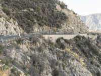 a road is winding away from the mountainside and steep slope of the valley, which runs into it