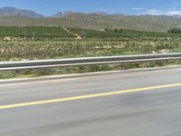 a person is riding a motorcycle on the road near mountains and trees, as seen through the windshield