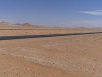 empty road near desert area with mountains in background, no people yet on it, in the distance are bushes and sparse clouds