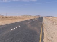 empty road near desert area with mountains in background, no people yet on it, in the distance are bushes and sparse clouds